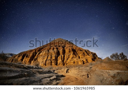 Red mountain of pyramid shape in the desert at night starry sky background. Astronomy photography of space and constellations.