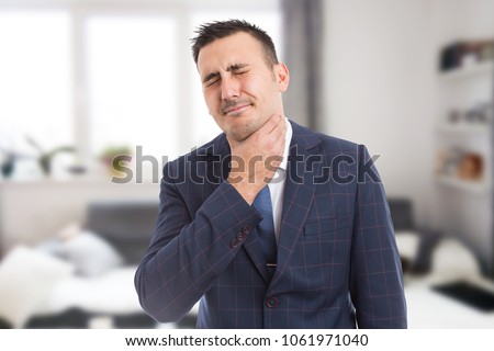Suited male grabbing painful neck as throat swallowing medical problem and flu cold or influenza concept Royalty-Free Stock Photo #1061971040