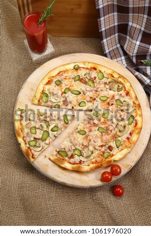 pizza with mushrooms chicken and cucumbers on a wooden stand