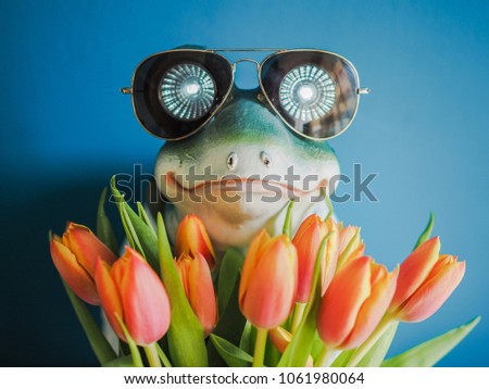 cool frog with sunglasses holding a bunch of flowers and looks like the hidden dream prince
