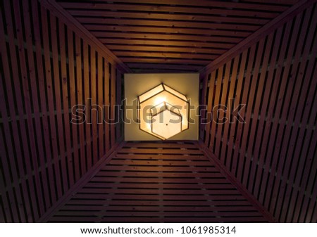 Polygonal design lamp glowing on wooden  kiosk ceiling. 