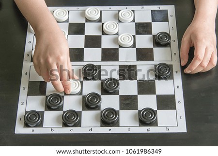 the child plays checkers at the table