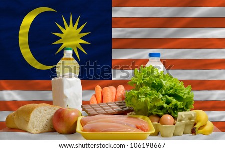complete national flag of malaysia covers whole frame, waved, crunched and very natural looking. In front plan are fundamental food ingredients for consumers, symbolizing consumerism