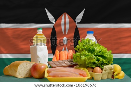 complete national flag of kenya covers whole frame, waved, crunched and very natural looking. In front plan are fundamental food ingredients for consumers, symbolizing consumerism