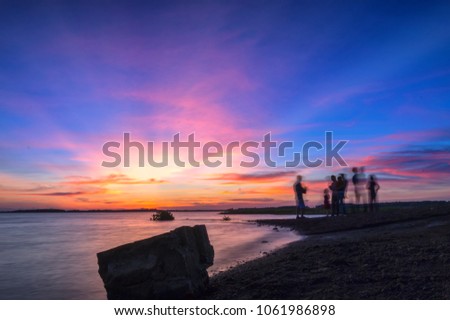 Colorful sunset in the river attracts family enjoying, take pictures, play together peacefully in the countryside.