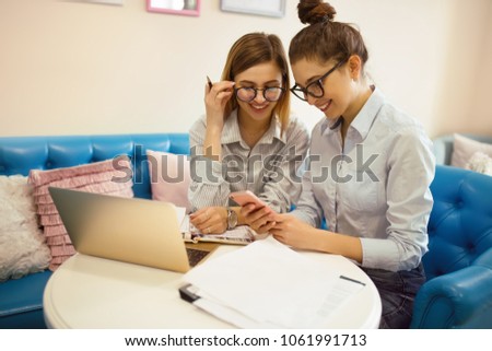 Two young and beautiful business women working at the café. Teamwork process.