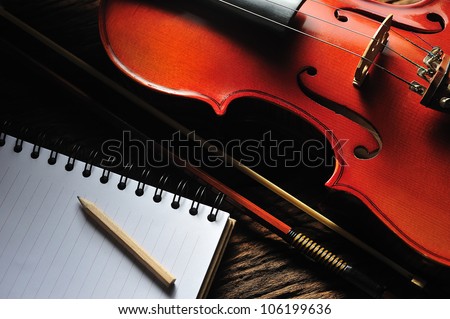 Violin and notebook on wooden table