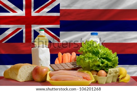 complete american state flag of hawaii covers whole frame, waved, crunched and very natural looking. In front plan are fundamental food ingredients for consumers, symbolizing consumerism