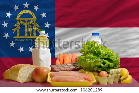 complete american state flag of georgia covers whole frame, waved, crunched and very natural looking. In front plan are fundamental food ingredients for consumers, symbolizing consumerism