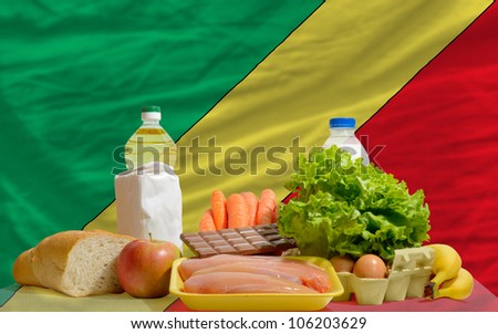 complete national flag of congo covers whole frame, waved, crunched and very natural looking. In front plan are fundamental food ingredients for consumers, symbolizing consumerism