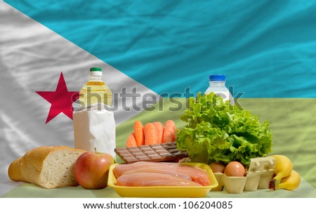 complete national flag of djibouti covers whole frame, waved, crunched and very natural looking. In front plan are fundamental food ingredients for consumers, symbolizing consumerism