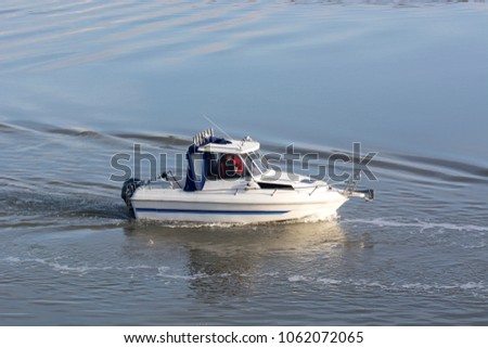 Small motor boat slowly moving on water Royalty-Free Stock Photo #1062072065