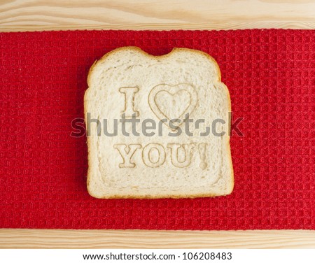 I love you bread. Slice of bread with I love you message on a red kitchen towel. The image can represent the concept of preparing food for the loved ones, sharing food or healthy eating.