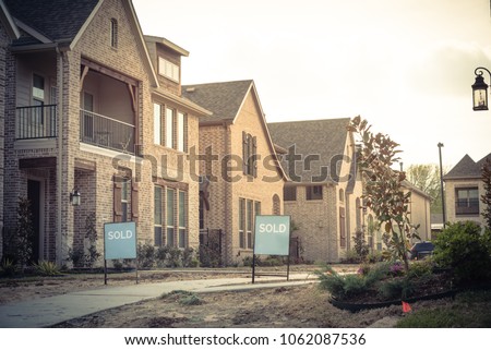 Row of newly built detached single-family homes and sold out sign. Medium size multiple lot properties in new-established community, construction zone with unfinished landscape Irving, Texas, USA