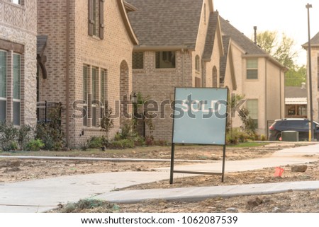 Close-up front porch of newly built detached single-family home with sold out sign. Brand new properties in new-established community, construction zone with unfinished landscape Irving, Texas, USA