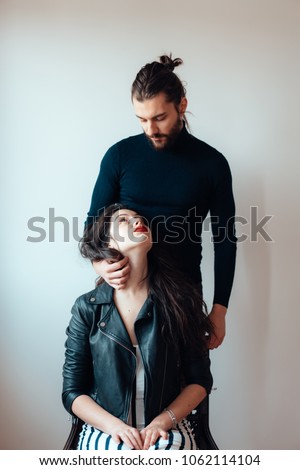 Girl sitting on a chair guy standing behind her, portrait on a light background