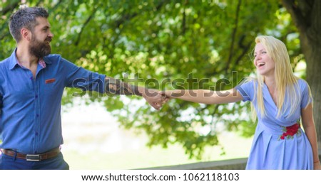 Bond and relationship concept. Bearded man walks with his girlfriend, hold hands. Couple in love walking, nature background, defocused. Happy couple in love rest together, hang out, have fun.