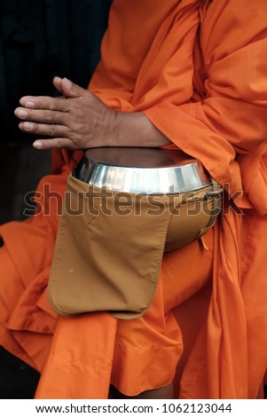 Selective focus at begging bowl belong to the monk arm.  The monk is praying to Buddha . Concept of Religion and Give food offerings to a Buddhist monk.