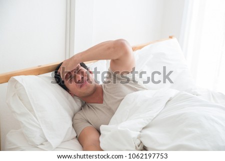 Asian man on the bed and hand on forehead. Illness,stress,headache caused by overworking or hard work. Royalty-Free Stock Photo #1062197753