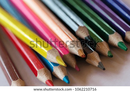 Pile of sharp coloured drawing pencils on table. Rainbow colors - red, yellow, blue, green, purple. Concept of art, crafts and kids having fun.