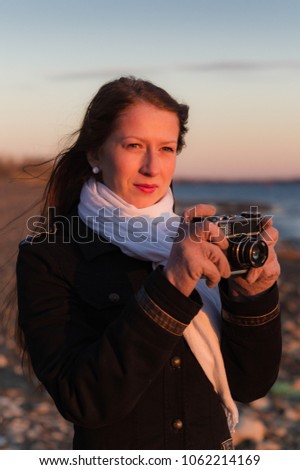 Girl photographer with an old camera taking pictures of the sunset