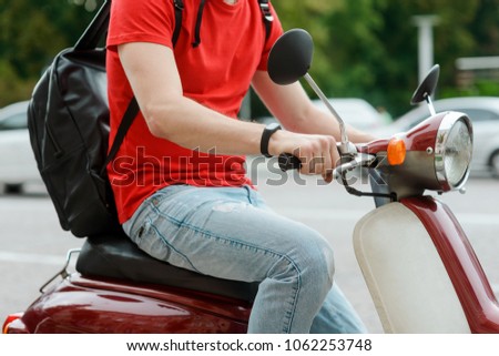 Detailed view on a young man driving an old-fashioned motorbike, running through city streets.