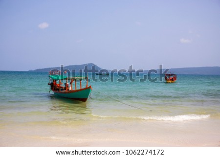 Cambodian traditional fishing boat near Koh Rong island seashore. Green and red wooden boat. White sand beach and turquoise blue sea. Koh Rong island landscape. Cambodian island vacation idyllic photo