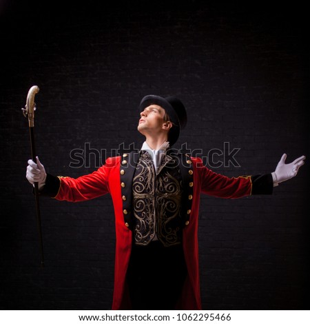 Showman. Young male entertainer, presenter or actor on stage. The guy in the red camisole and the cylinder spreading hands