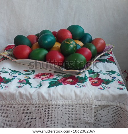 The picture shows an egg on a tray with an old towel.The egg is painted pink,red, blue and green.