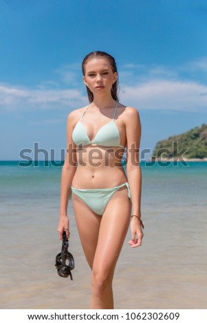 Fashion model demonstrates leotard and diving mask on the water background. The concept of active life and water sports.