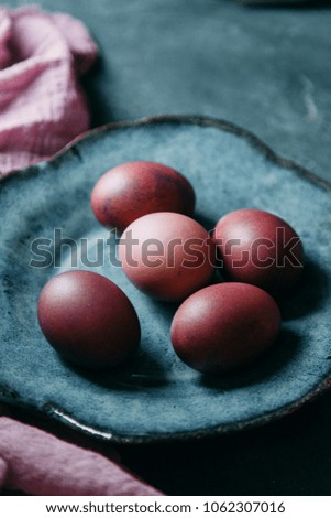 Painted Easter eggs with fabric and tea decor, on dark textured background. Gamma blue purple in natural light