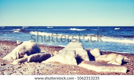 Frozen rocks on a beach, color toned picture, selective focus.