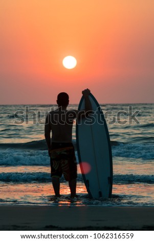 surfer on beach at sunset