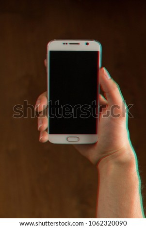 Hand holding smartphone, mobile phone facing up, closeup. Color channels effect on the phone and hands. Blue and red channels.