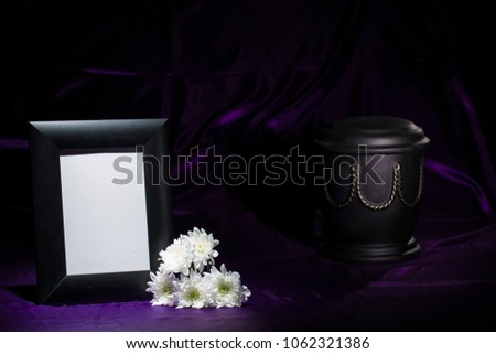 black urn with golden decoration, white chrysanthemum, black  mourning frame on deep purple background for sympathy card