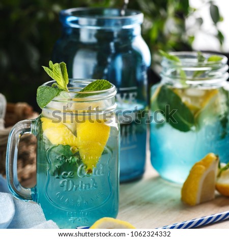 Citrus lemonade water with lemon sliced , healthy and detox water drink in summer on wooden table on a background green foliage