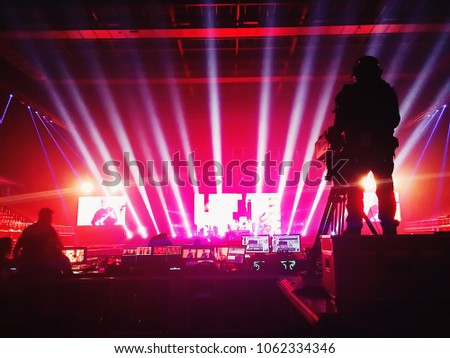 Live concert background with silhouette production team working or technical rehearsal for artist performance on blurred background of stage with lighting at music hall. Music Business Concept.