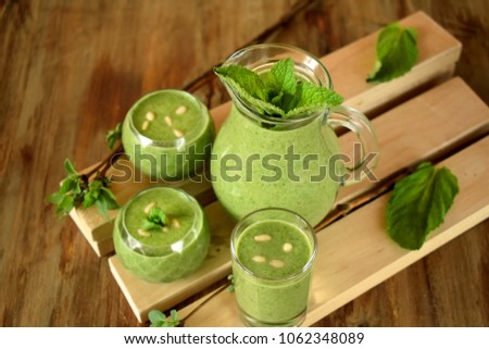 Green smoothie in glass vessels on wooden background 