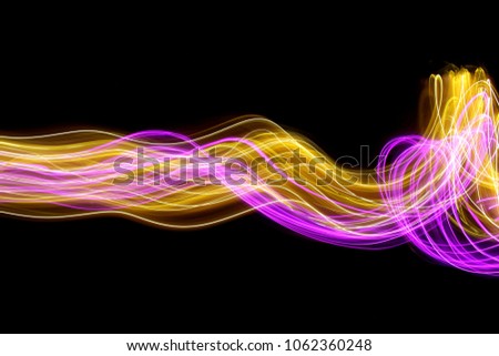 Pink and gold light painting photography, long exposure photo of fairy lights in a rippling, curvy wavy pattern, against a black background