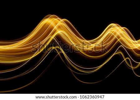 Gold light painting photography, long exposure photo of metallic fairy lights against a black background