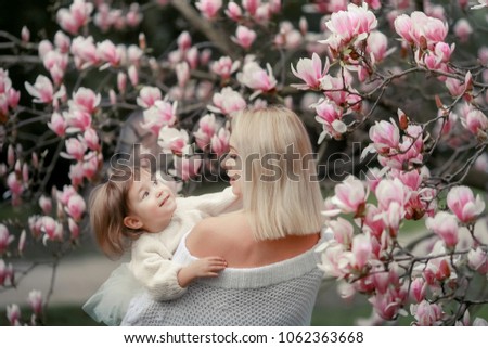Mom and daughter in the blossoming magnolia garden