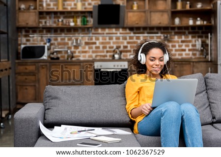 attractive young woman working with laptop and listening music at home Royalty-Free Stock Photo #1062367529