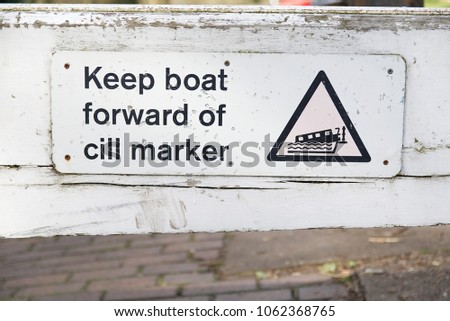 Old canal lock sign with guidance to Keep boat forward of cill marker on wooden lock gate