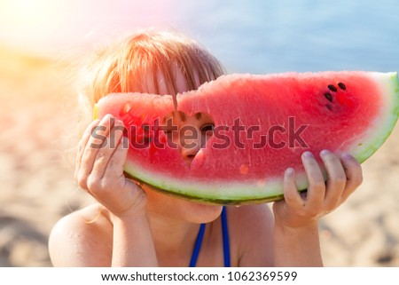 Little girl eating watermelon on the beach
