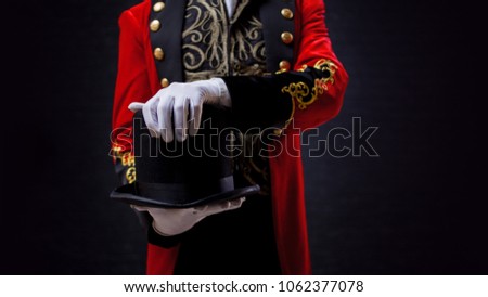 Magician. Close-up of hand in gloves The guy in the red camisole and the cylinder. Bright tailcoat, suit
