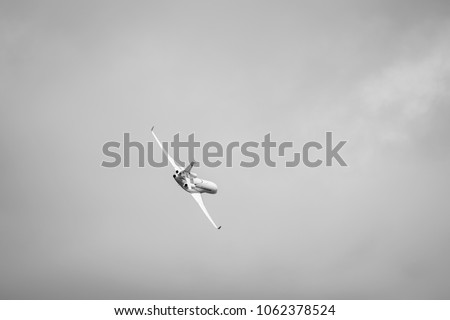 Black and white photo of a commercial aircraft in the sky taking a curve after take off.