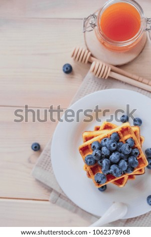 Belgian waffles with blueberries on the light wooden table. Healthy breakfast. 
Vertical format. Top view. Copy text space.