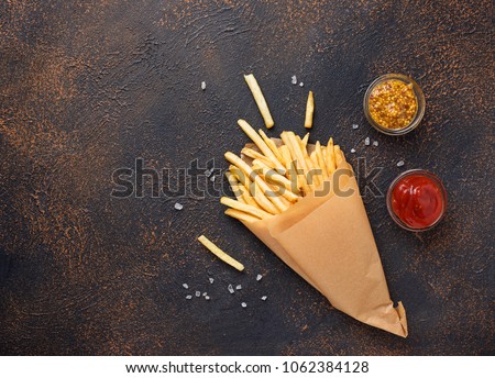 French fries in a paper bag with sauces. Top view Royalty-Free Stock Photo #1062384128