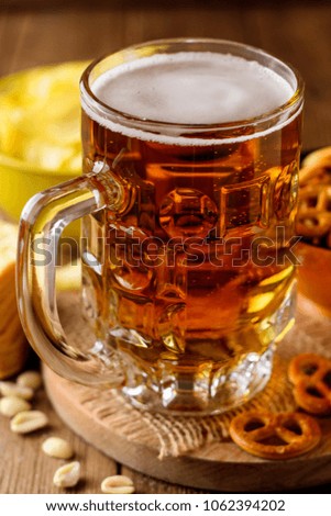Mug of beer and snacks on wooden background. Selective focus.