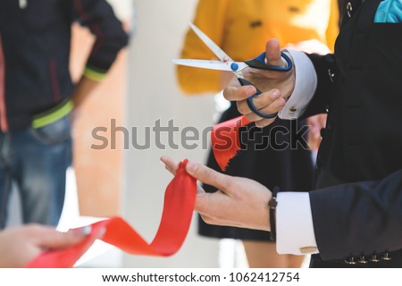 Cutting a red ribbon with scissors Royalty-Free Stock Photo #1062412754